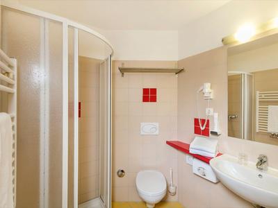 Helles Badezimmer mit Runddusche, Wand-WC, Waschtisch, Handtuchheizung und Wandfön.