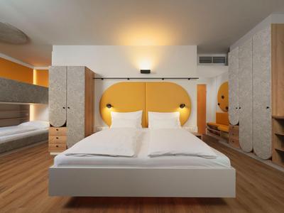 Modernes Schlafzimmer mit Doppelbett, gelbem Wanddesign und Holzmöbeln in einem Hotelzimmer.