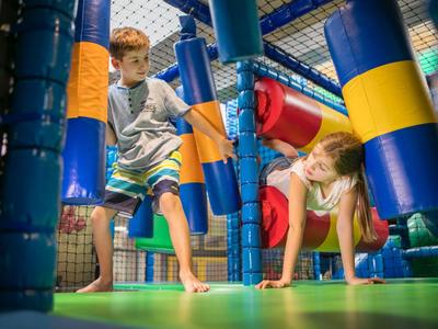 Kinder spielen und klettern in einem bunten Indoor-Klettergerüst in einem Hotelspielbereich.