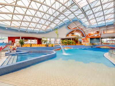 Großer Innenpool in einem Hotel mit Glasdach, Liegestühlen und moderner Einrichtung.