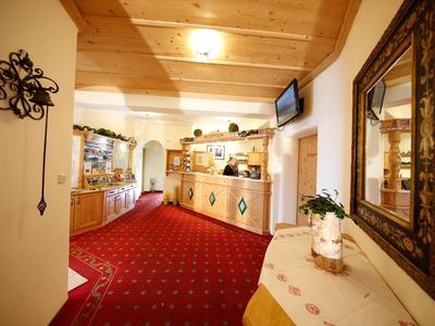 Gemütliche Hotellobby mit rotem Teppich, Holzdecke und Rezeption im Hintergrund