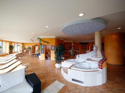 Salon d'hôtel avec sièges blancs, plantes et tons de couleurs chaudes.