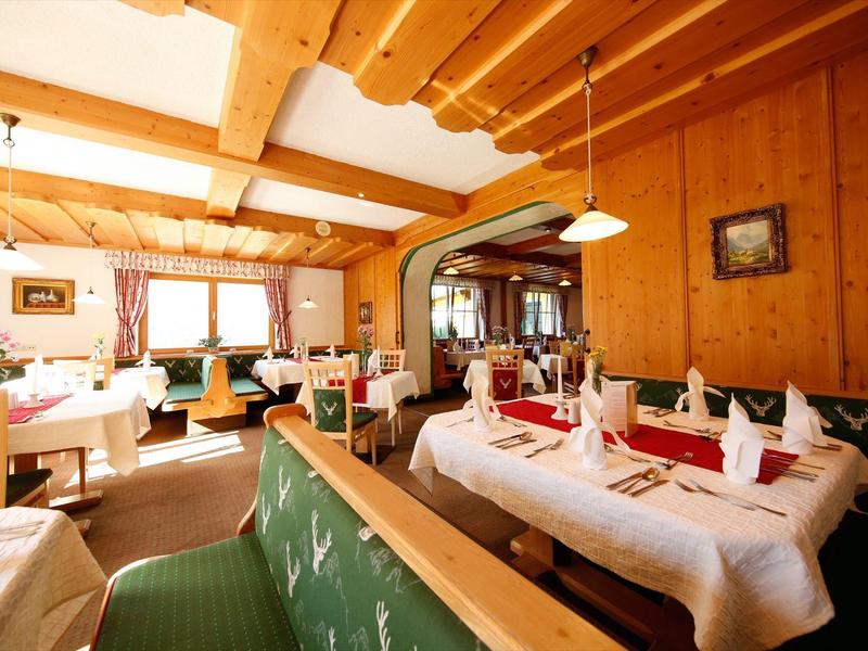 Restaurant confortable avec murs en bois, tables dressées et lumière naturelle.