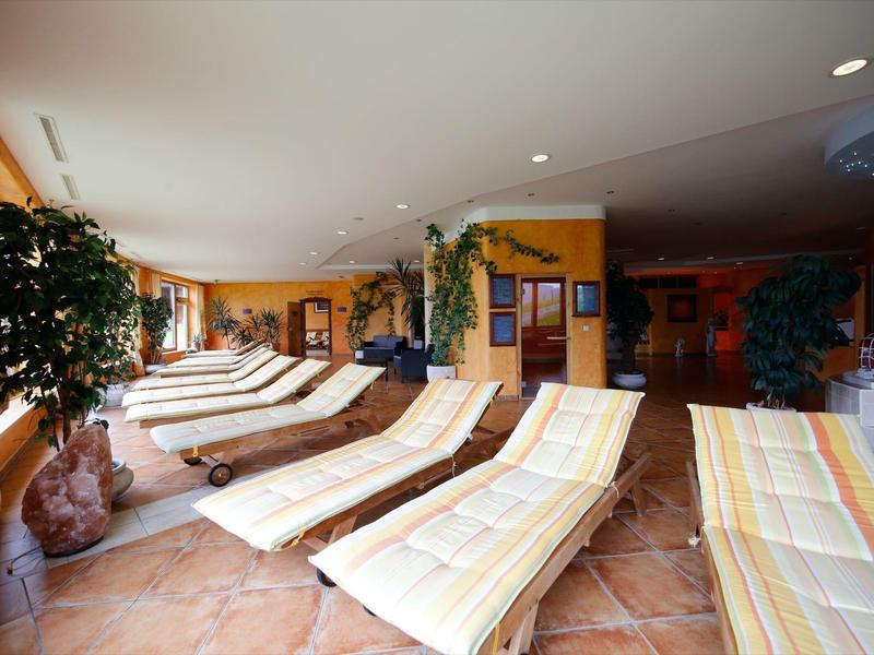 Chaises longues avec coussins colorés dans une pièce de bien-être lumineuse et accueillante avec des plantes.