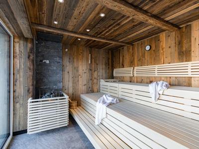Helle Holzbänke und Wände in moderner Sauna mit Glasfront und Holzdecke.