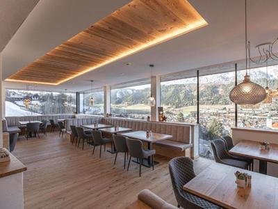 Heller Hotel-Speisesaal mit Holzboden, großen Fenstern und modernen Möbeln.