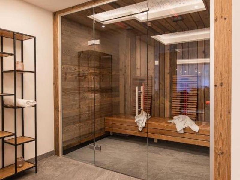 Moderne Sauna mit gläserner Tür, Holzbank und elegantem, perforiertem Deckenlicht.