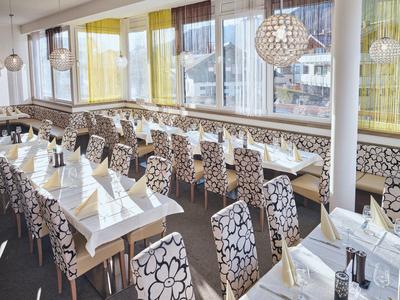 Innenansicht eines hellen Restaurants mit floralen Stuhlbezügen und gedeckten Tischen.