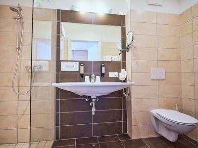 Modernes Badezimmer mit hellen und dunklen Fliesen, Waschbecken, Toilette und großer Spiegelwand.