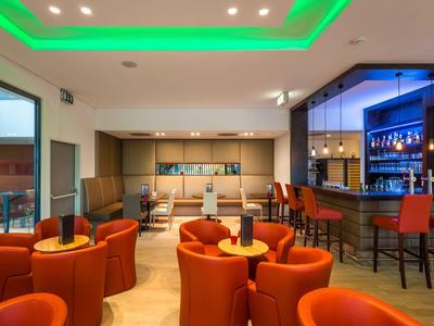 Moderne Hotelbar mit orangen Sesseln, Holzboden und gemütlicher Beleuchtung.