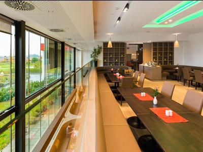 Modern eingerichteter Speisesaal mit großen Fenstern und Grünblick