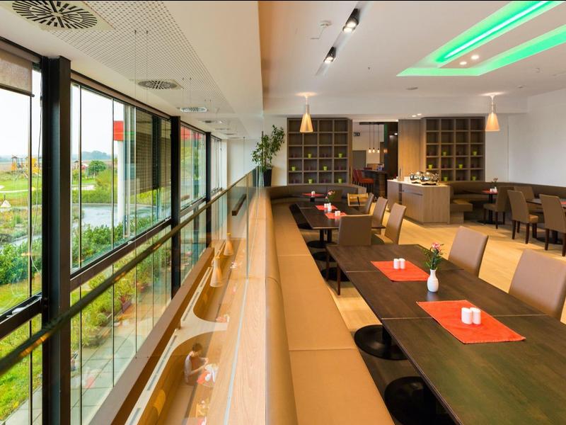 Modern eingerichteter Speisesaal mit großen Fenstern und Grünblick