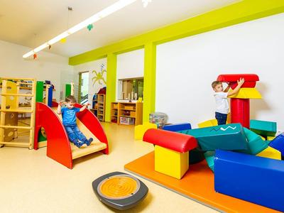 Bunter Spielbereich mit Rutsche, Bausteinen und Sitzkissen in Innenraum eines Hotels