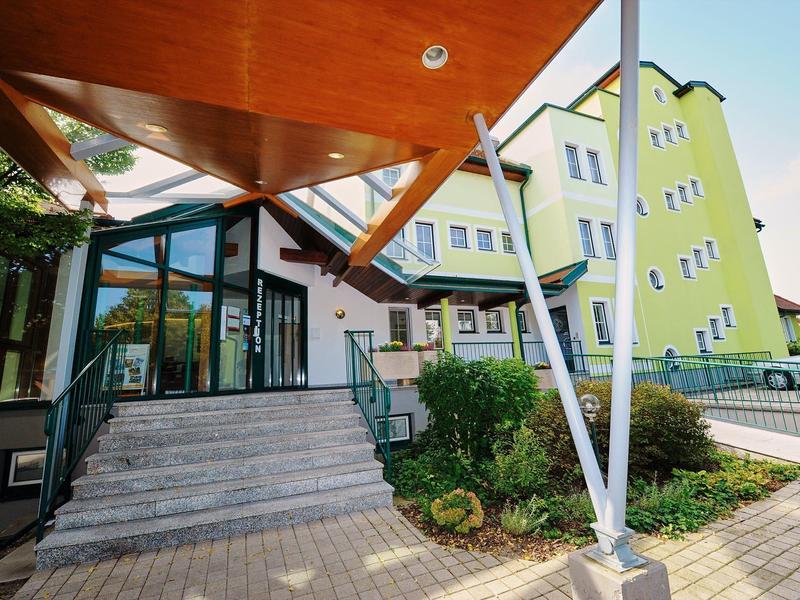 Eingang zu einem Hotel mit großen Treppen und einem markanten orangefarbenen Vordach