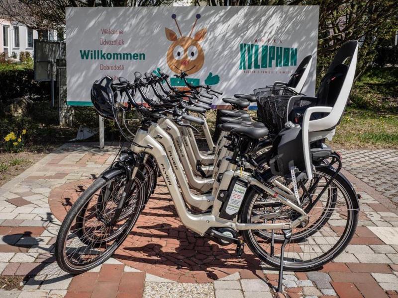 Mehrere geparkte E-Bikes mit Kindersitzen vor einem Willkommensschild im Tierpark.