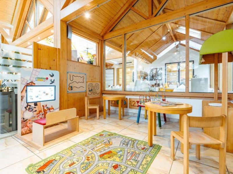 Heller, moderner Kinderspielbereich in einem Hotel mit Holzmöbeln und Teppich.