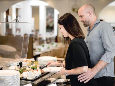Ein Paar nimmt Essen vom Buffet in einem hellen Restaurant mit modernem Interieur.