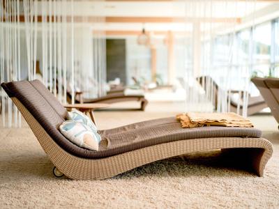 Moderner Liegestuhl in einem hellen, stilvollen Hotel-Spa-Bereich mit großen Fenstern.