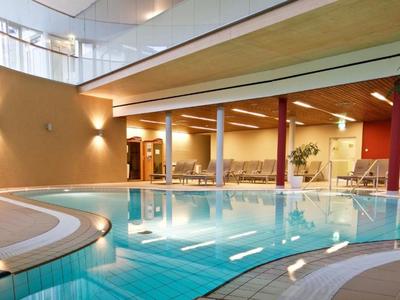 Moderner Innenpool mit runder Form und Sitzgelegenheiten in einem Hotelbereich.