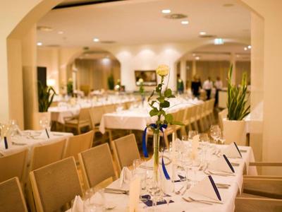 Eleganter Bankettsaal mit gedeckten Tischen und schlichter Dekoration für ein Hotel-Event.