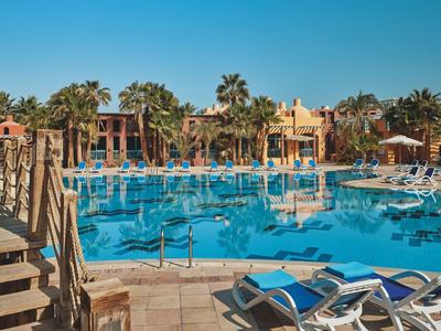 Grande piscine avec chaises longues et palmiers dans une zone hôtelière ensoleillée