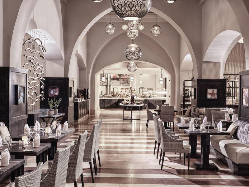 Elegantes Restaurant mit hohen Bögen, modernen Pendelleuchten und gedeckten Farbnuancen.