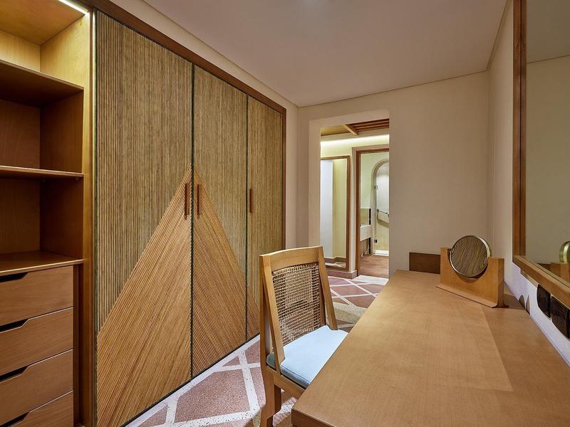 Kompakter Raum mit Schrank, Schreibtisch, Holzstuhl und spiegelndem Kosmetikspiegel.