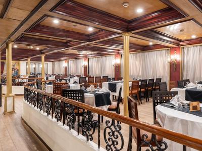 Restaurante elegante con techo de vigas de madera, manteles blancos y luz acogedora.