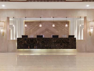 Eleganter Hotel-Check-in mit dunkler Marmor-Theke und warmem Beleuchtungskonzept.