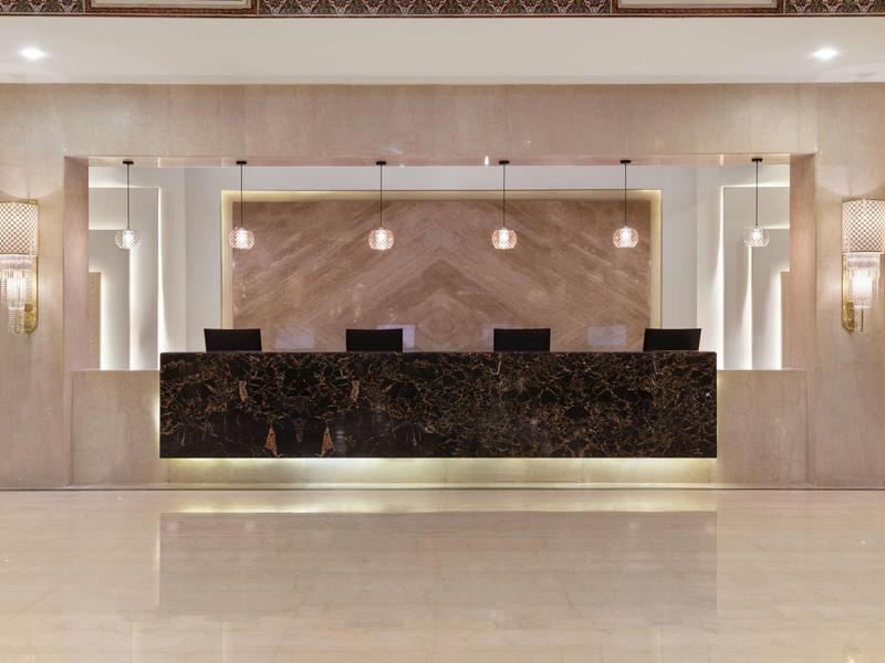 Nowoczesny hotelowy recepcja z czarnym marmurowym blatem i jasnobeżowymi ścianami.