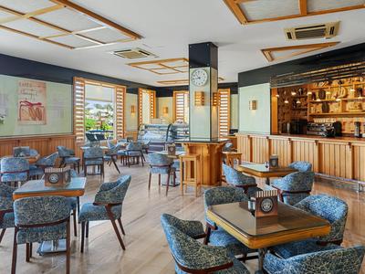 Ristorante luminoso con mobili in legno, sedie blu e grandi finestre.