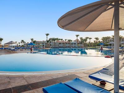 Grande piscina all'aperto con lettini e ombrelloni in un resort alberghiero.