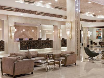 Lichte, elegante hotellobby met moderne zithoeken en glanzende marmeren vloer.