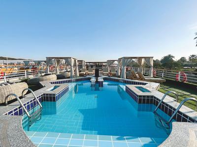 Bella piscina all'aperto con aree salotto e acqua azzurra limpida sotto un cielo sereno.