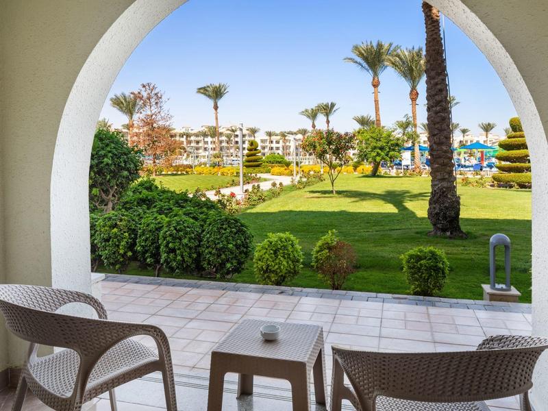 Vue sur un jardin verdoyant depuis une terrasse avec deux chaises et une table.
