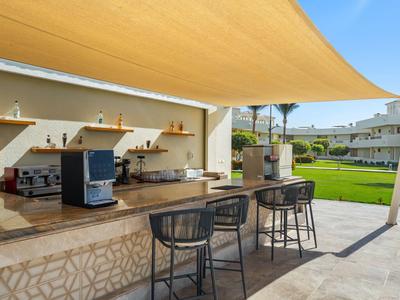 Área de ocio al aire libre con bar, asientos y toldo en un complejo hotelero.