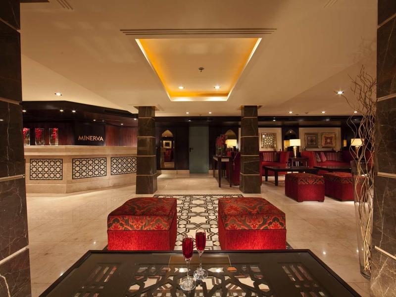 Eleganter Innenraum mit warmem Licht, roten Sesseln und dunklen Marmorsäulen, gemütliche Lounge-Atmosphäre.