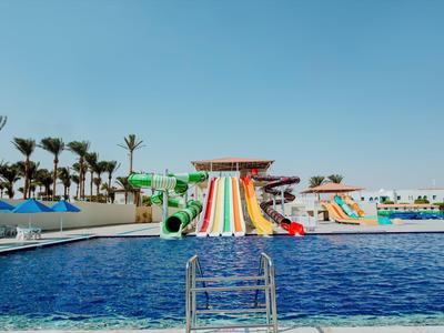 Waterpark met zwembad en kleurrijke glijbanen onder een heldere blauwe lucht.