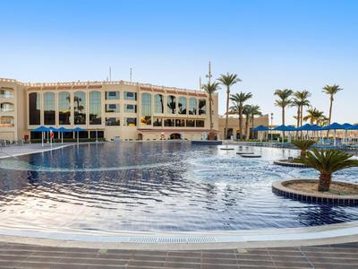 Complexe hôtelier moderne avec grande piscine extérieure et palmiers sous un ciel clair