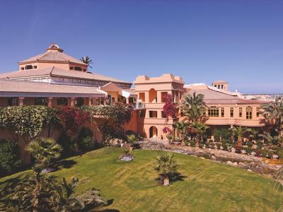 Grande resort con giardini curati e palme sotto un cielo azzurro limpido.
