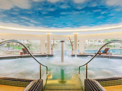 Modernes Hallenbad mit Whirlpool und Decke in Himmeloptik in einem Hotel