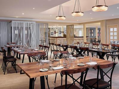 Modern hotel restaurant with wooden tables and black chairs, elegantly set in a bright atmosphere.
