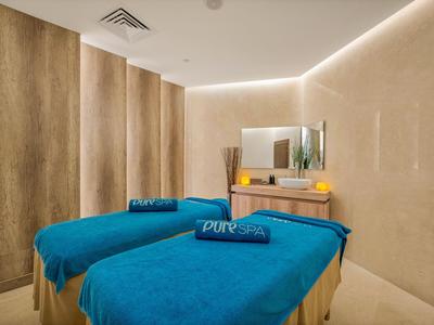 Zwei Behandlungsbetten mit blauen Handtüchern in einem beruhigenden Spa-Raum.