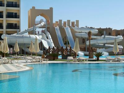 Grande piscina con scivoli d'acqua e ombrelloni in un resort alberghiero sotto un cielo sereno.