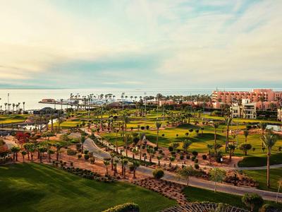 Ampio giardino con sentieri e palme davanti agli edifici dell'hotel vicino al mare al tramonto