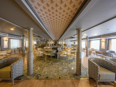 Amplia y elegante zona de salón en hotel con mobiliario moderno y suelo de mármol.