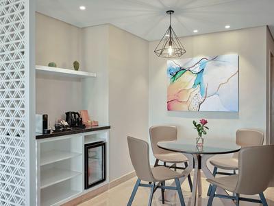 Área de comedor moderna con mesa redonda, sillas, minibar y arte abstracto en tonos claros.