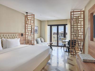 Elegante hotelkamer met groot bed, stijlvolle scheidingswanden en balkon met uitzicht.