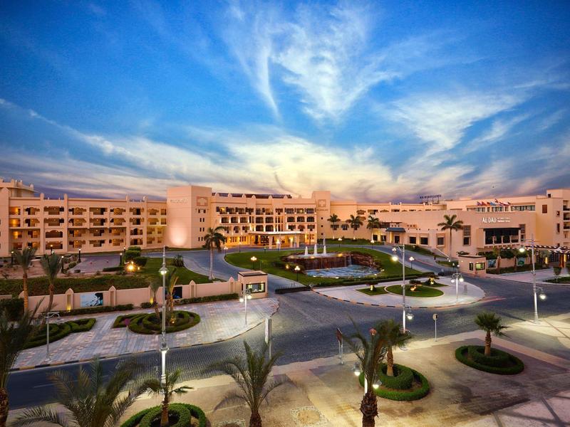 Duży budynek hotelowy o zachodzie słońca z jasnym niebieskim niebem i palmami na pierwszym planie