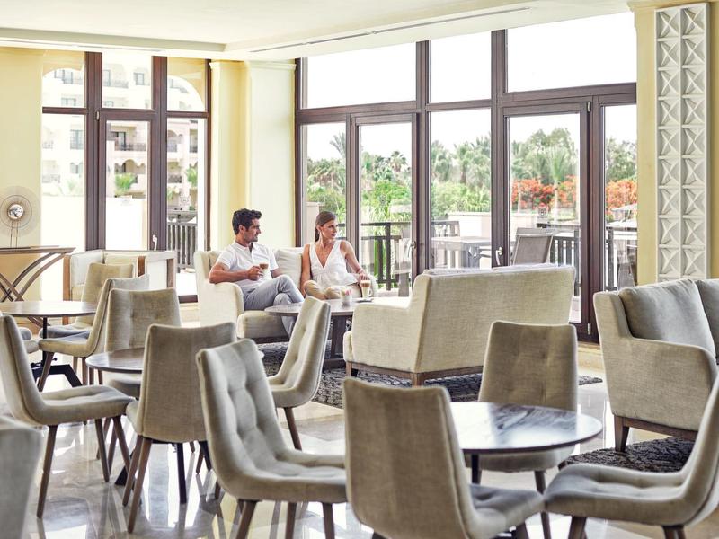 Nowoczesny pokój hotelowy z wygodnymi krzesłami i dużymi oknami z widokiem na ogród.